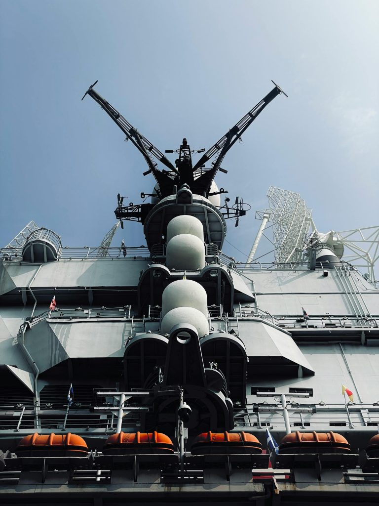 Low angle view of a military navy ship under a clear sky, symbolizing strength and power.