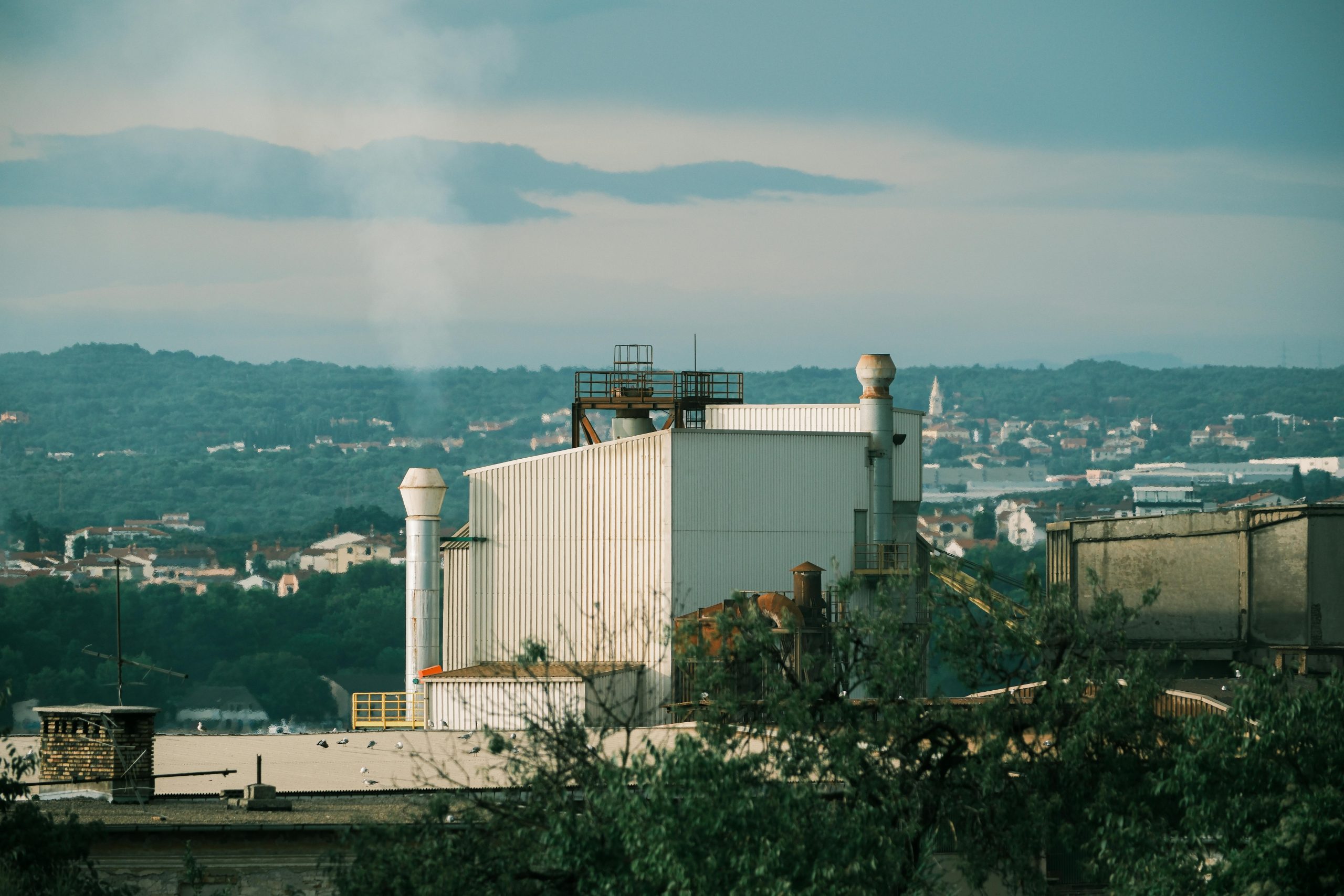 A factory building set against the scenic background of Hırvatistan's verdant landscape.