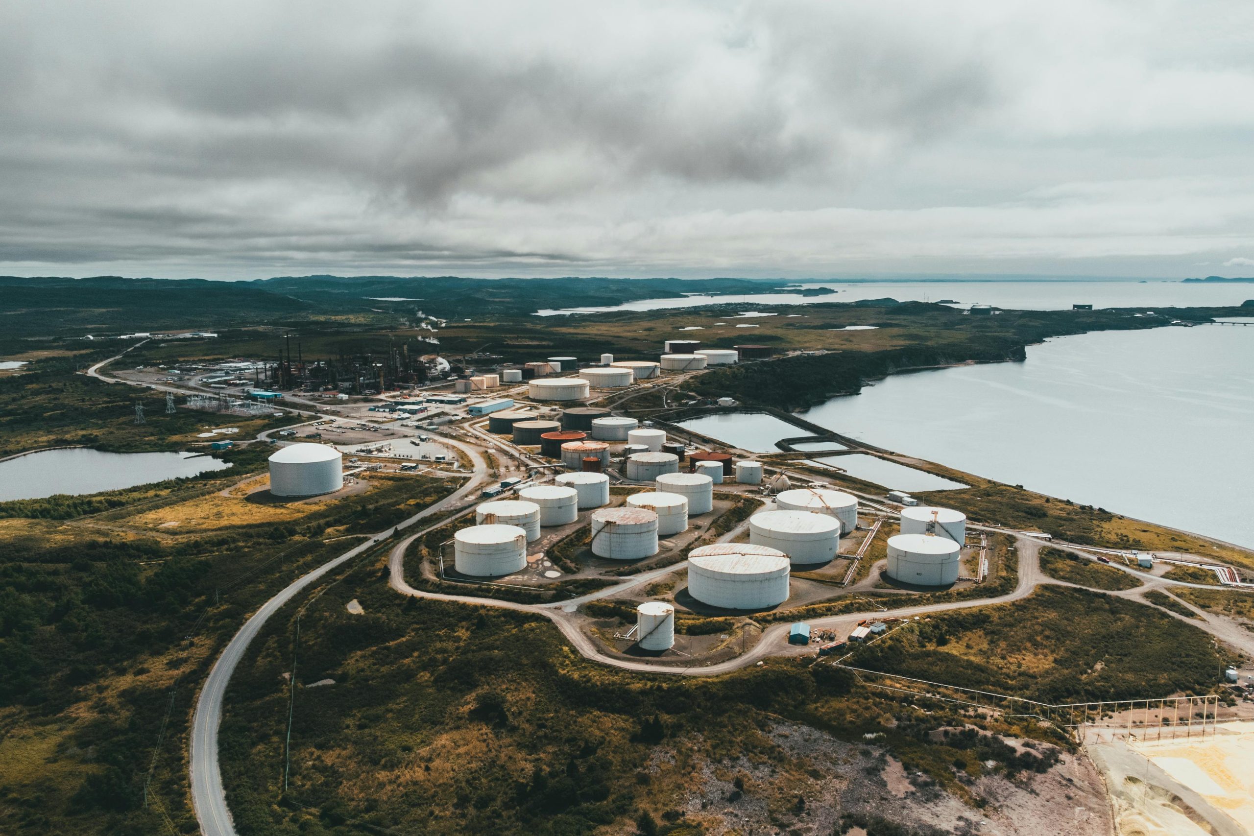 Aerial shot of industrial storage tanks near a waterfront landscape, showcasing industrial infrastructure.